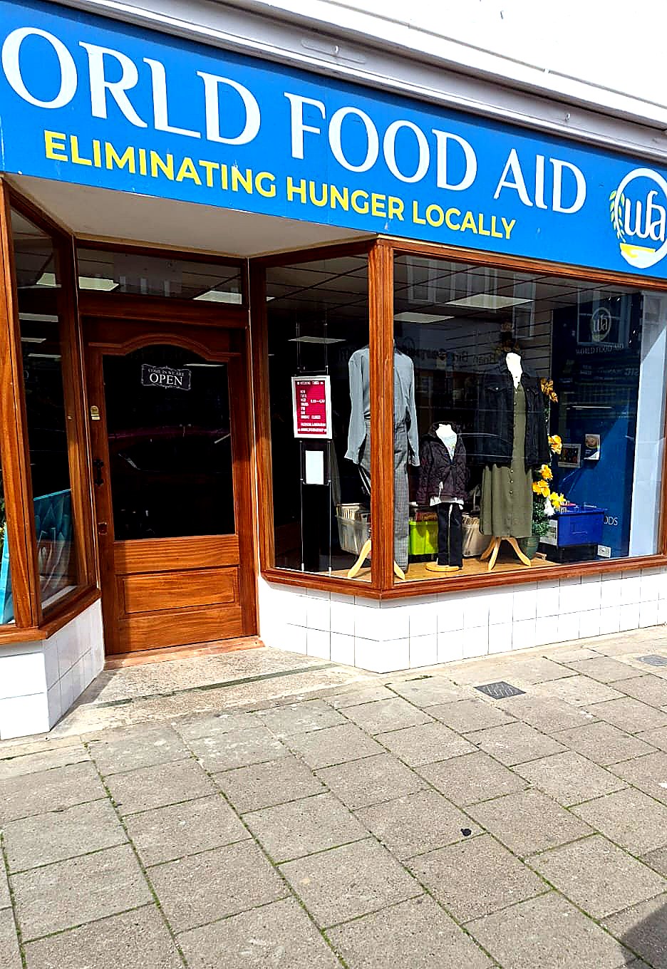 Traditional hardwood entrance door with arched glazing detail and blue branded fascia signage
