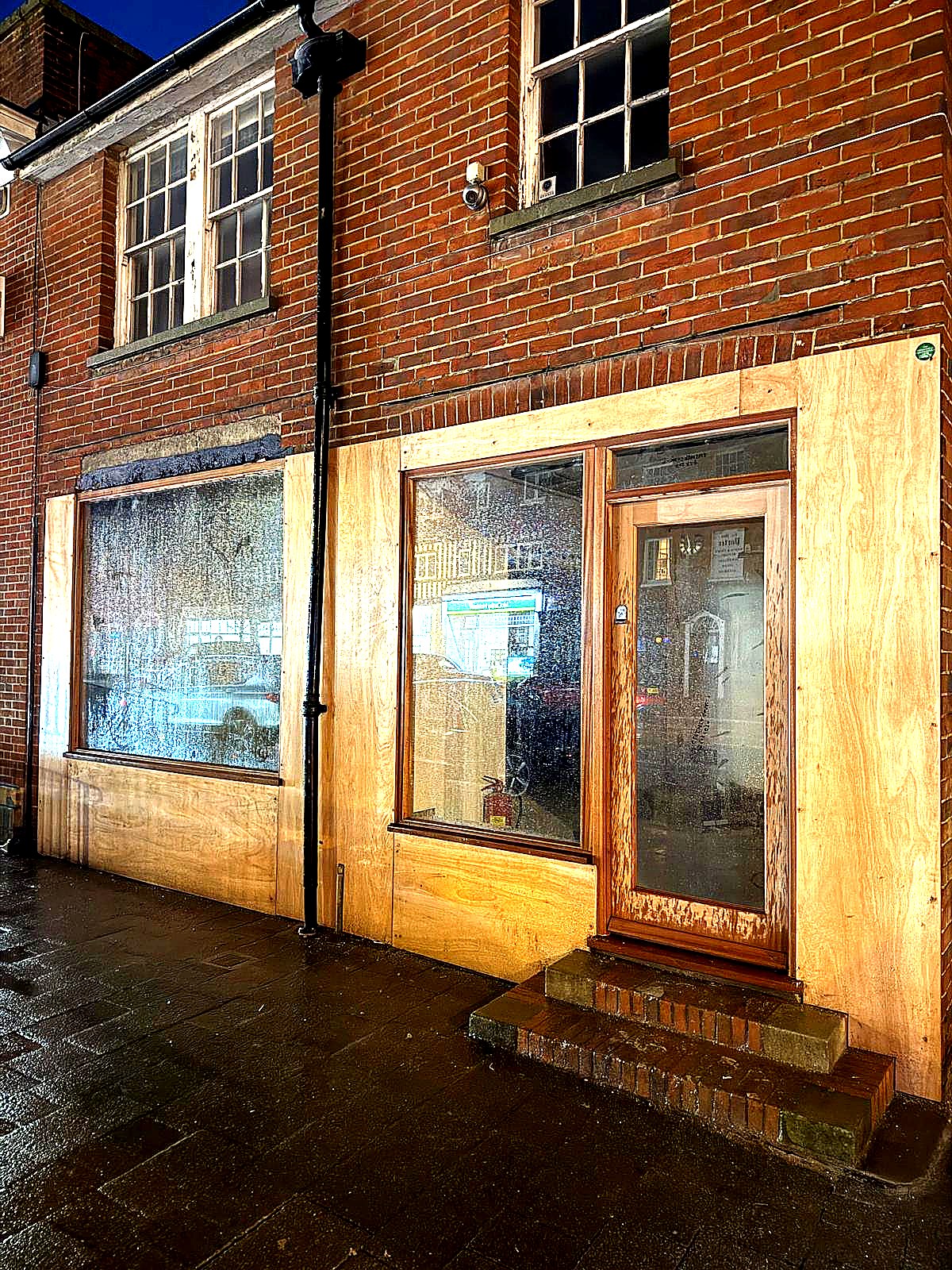 During install — protective plywood boarding around new windows after a wet evening shift