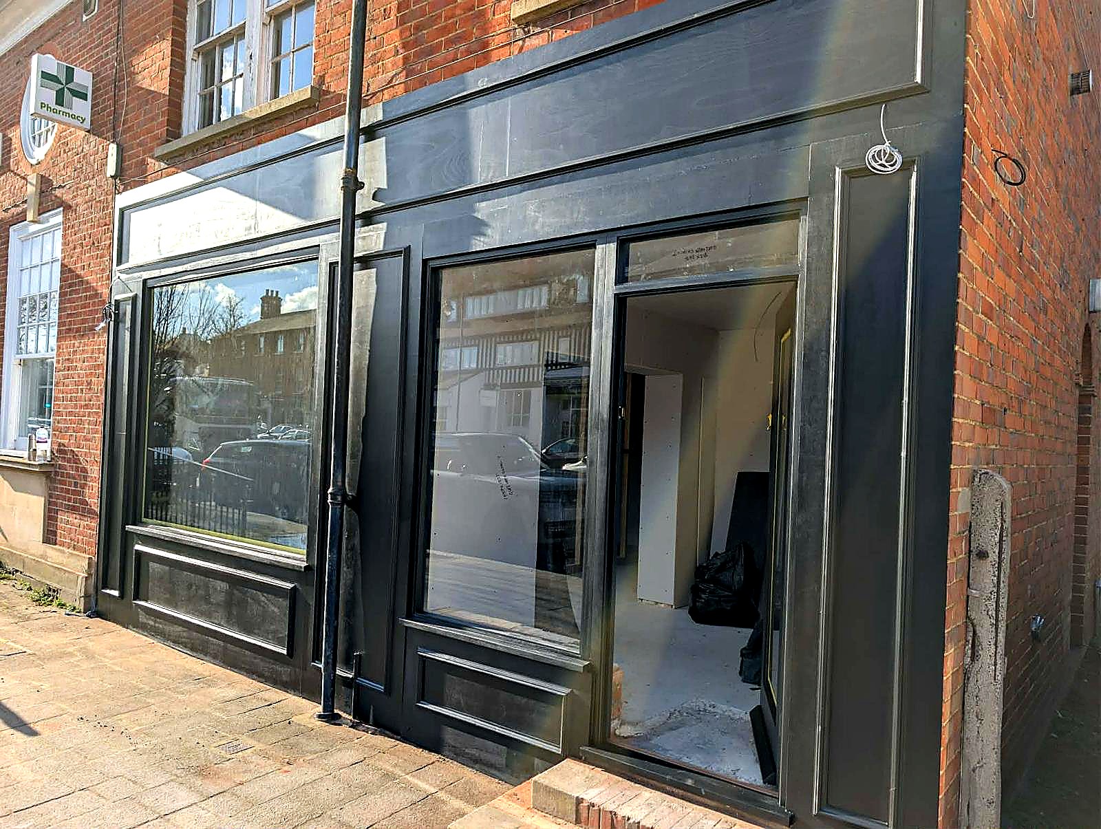 After — frontage painted in deep black satin, pre-signage, viewed from the side