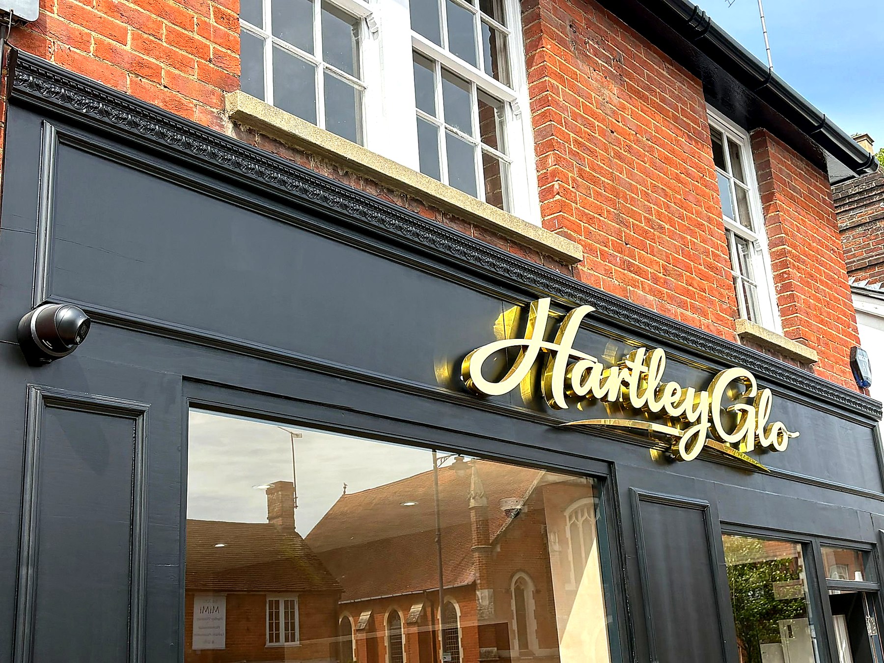 Detail — gold script signage with the ornate dentil cornice running above
