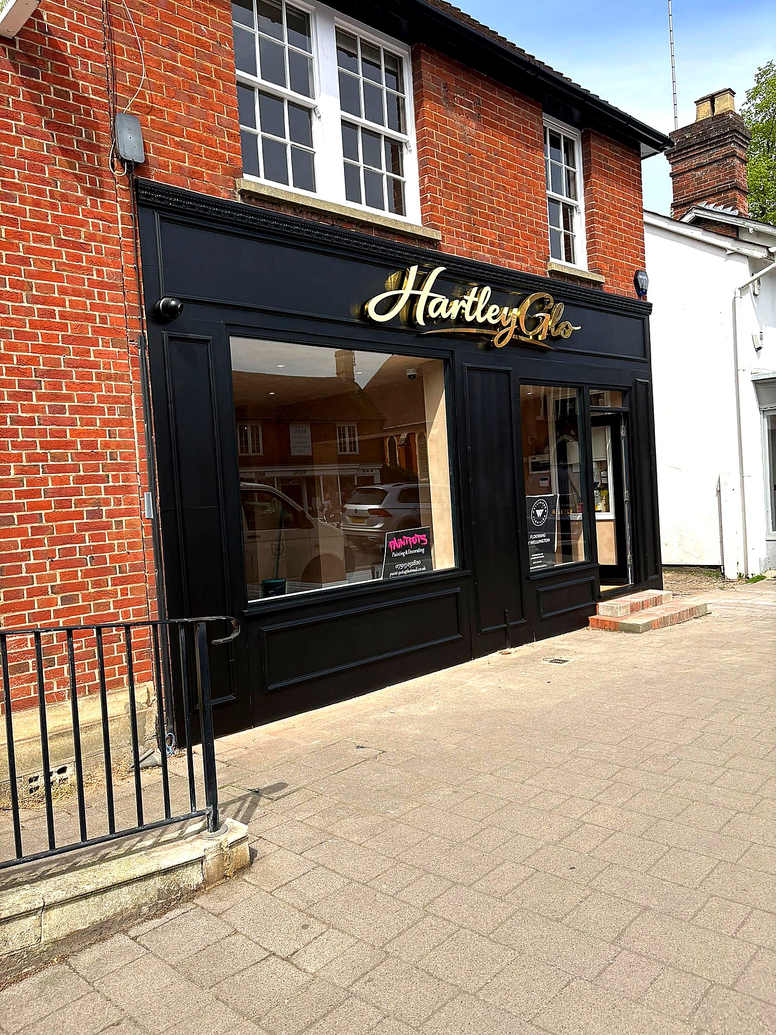 Completed — side angle in full sunshine showing the entrance steps and brick context